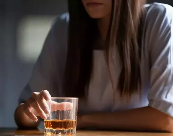 Frau sitzt am Tisch mit einem Glas eines alkoholischen Getränks