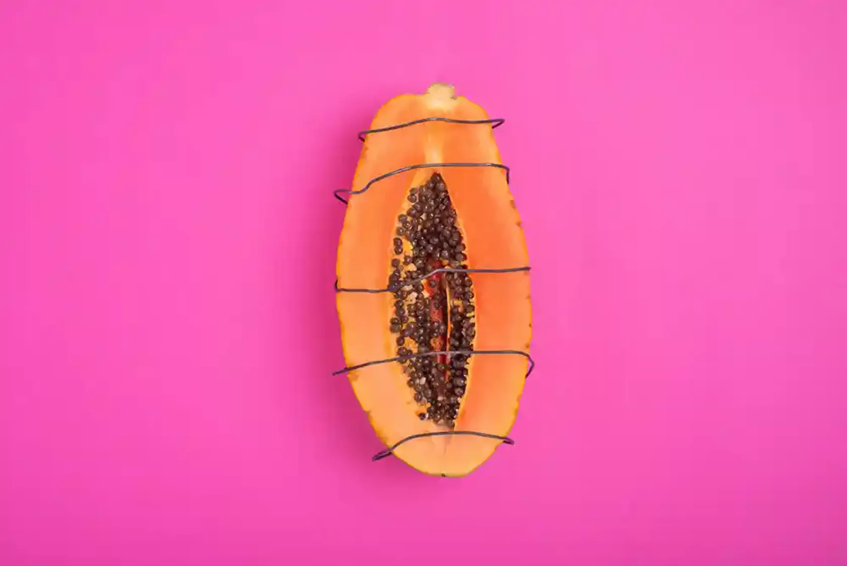 Eine aufgeschnittene Papaya, mit Draht umwickelt, als Symbol für Schmerzen im Intimbereich der Frau, Vulvodynie, Scheidenkrämpfe