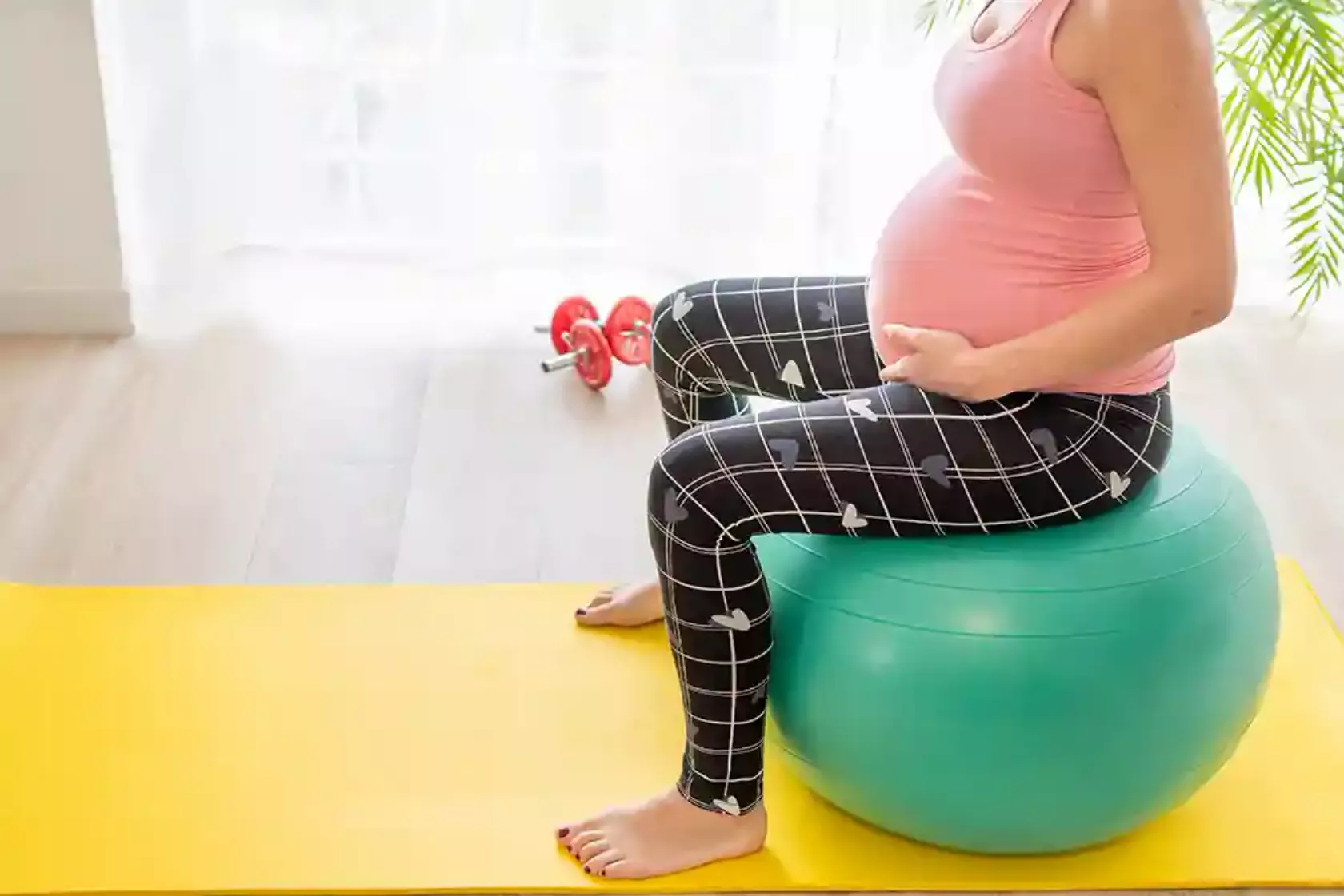 Schwangere sitzt auf einem Gymnastikball.