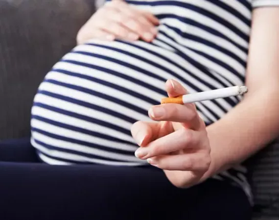 Schwangere Frau mit brennender Zigarette in der Hand
