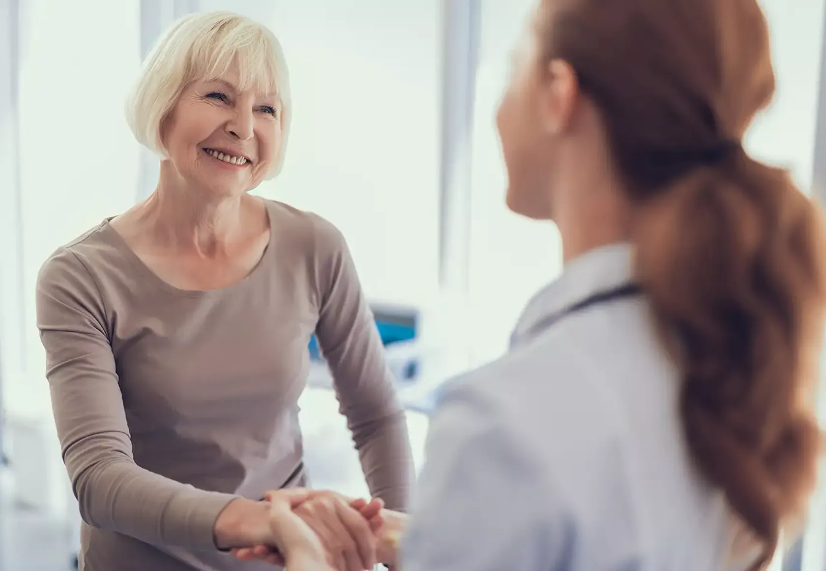 Lächelnde Patientin mittleren Alters mit ihrer Ärztin im Gespräch.