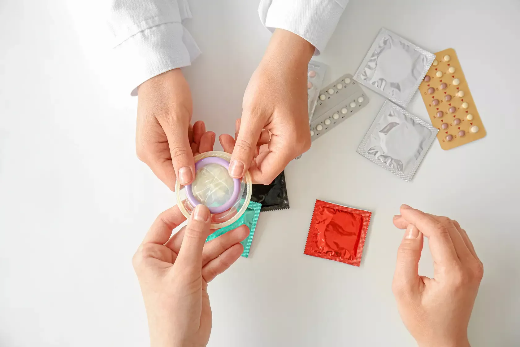 Der Gynäkologe zeigt verschiedene Verhütungsmittel wie Pille, Kondome, Diaphragma