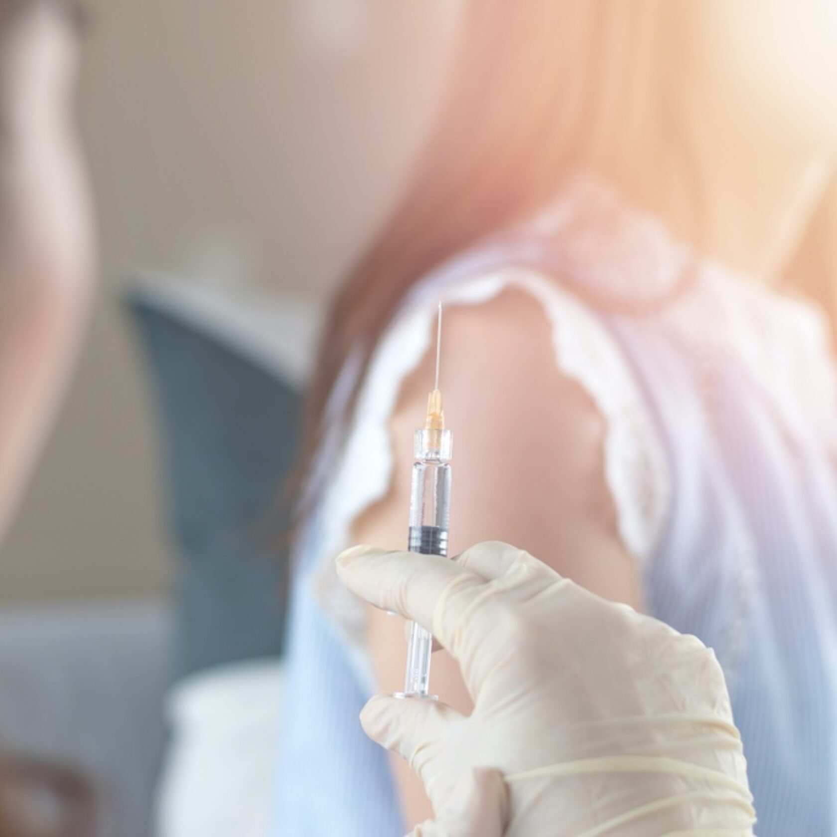 Aufgezogene Spritze mit Impfung vor dem Arm eines jungen Mädchens.