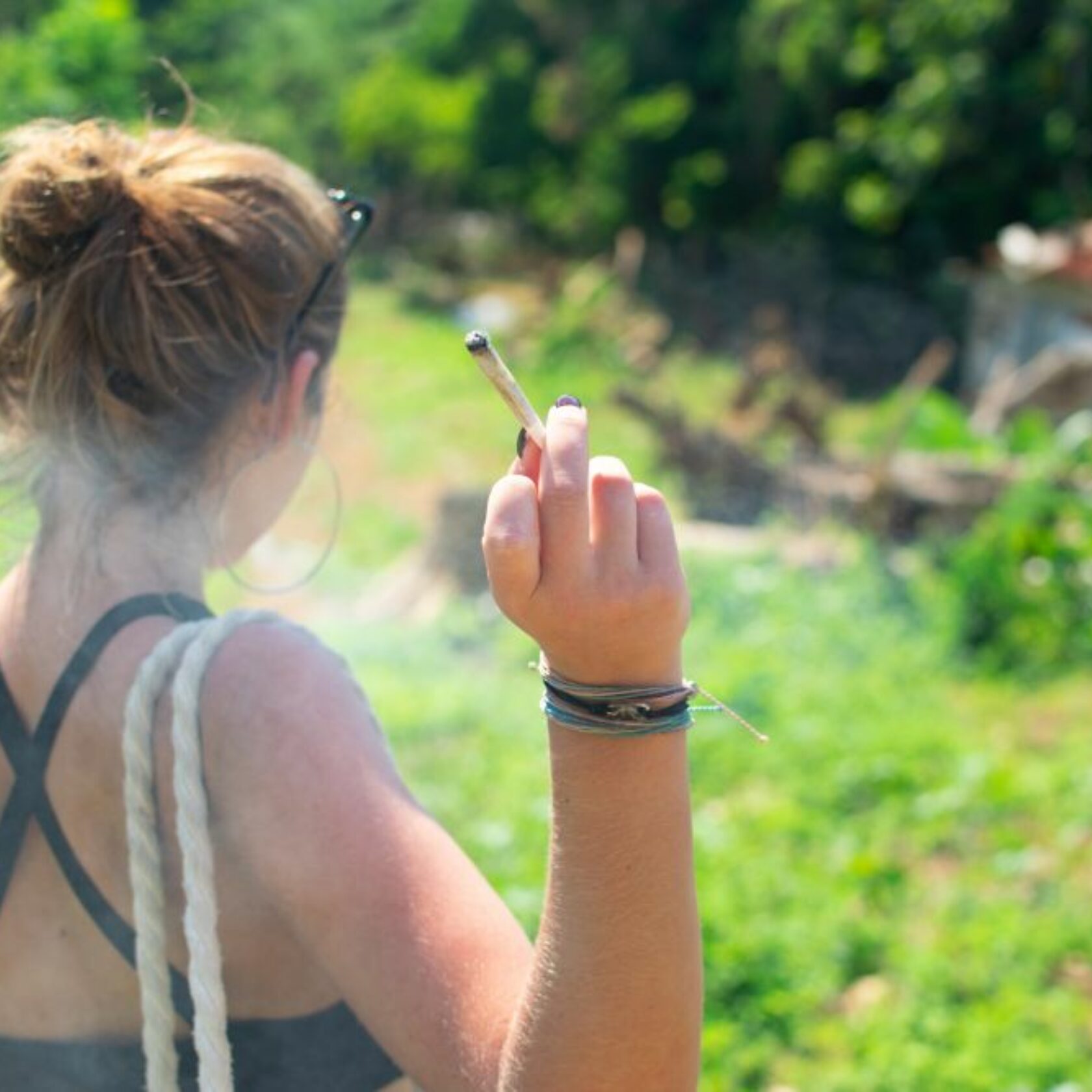 Junge Frau hält einen rauchenden Joint. Canabiskonsum in der Schwangerschaft ist bedenklich.