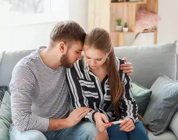 Junges Paar traurig mit Schwangerschaftstest zuhause