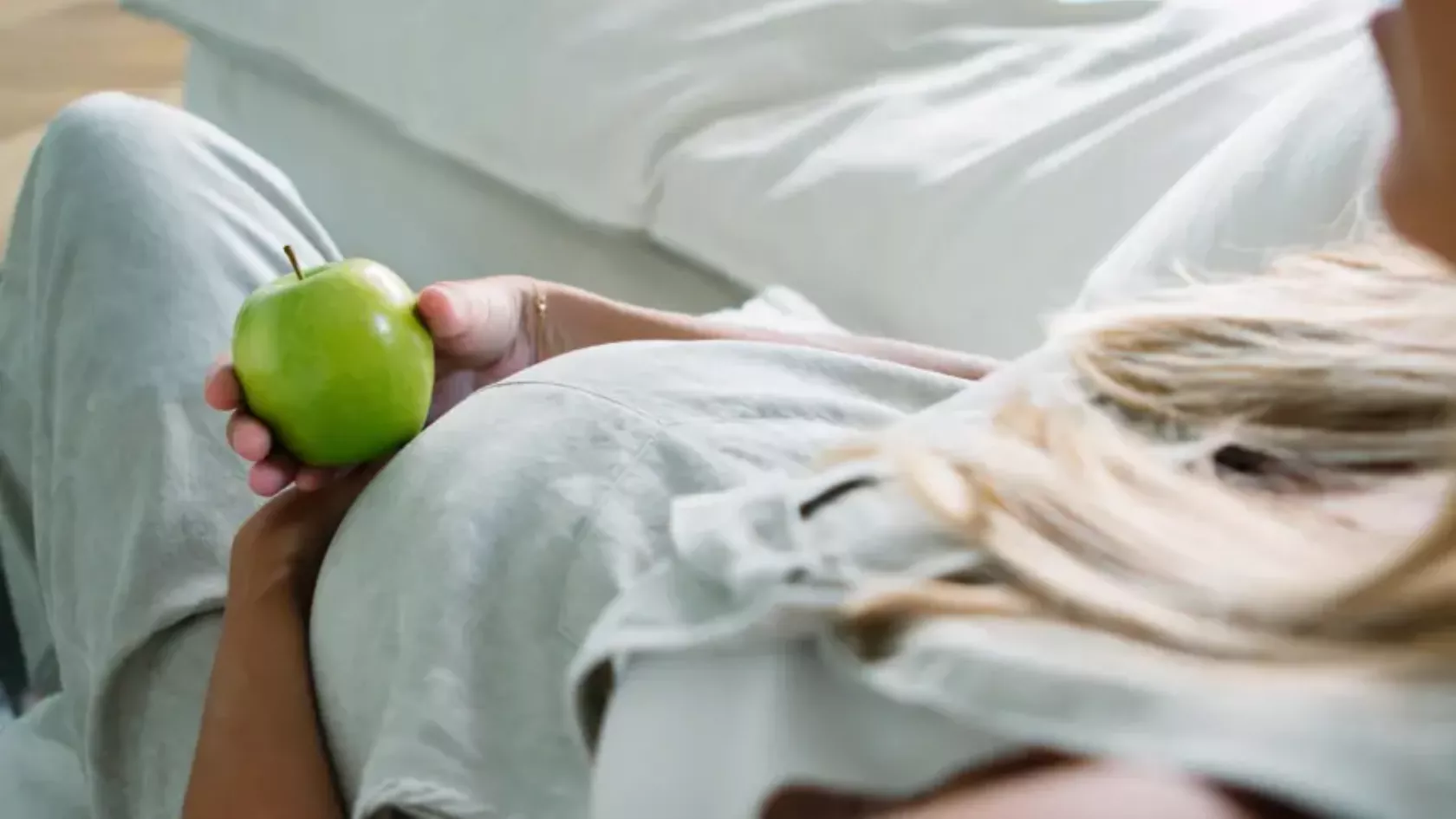 Vegane Schwangere isst einen Apfel