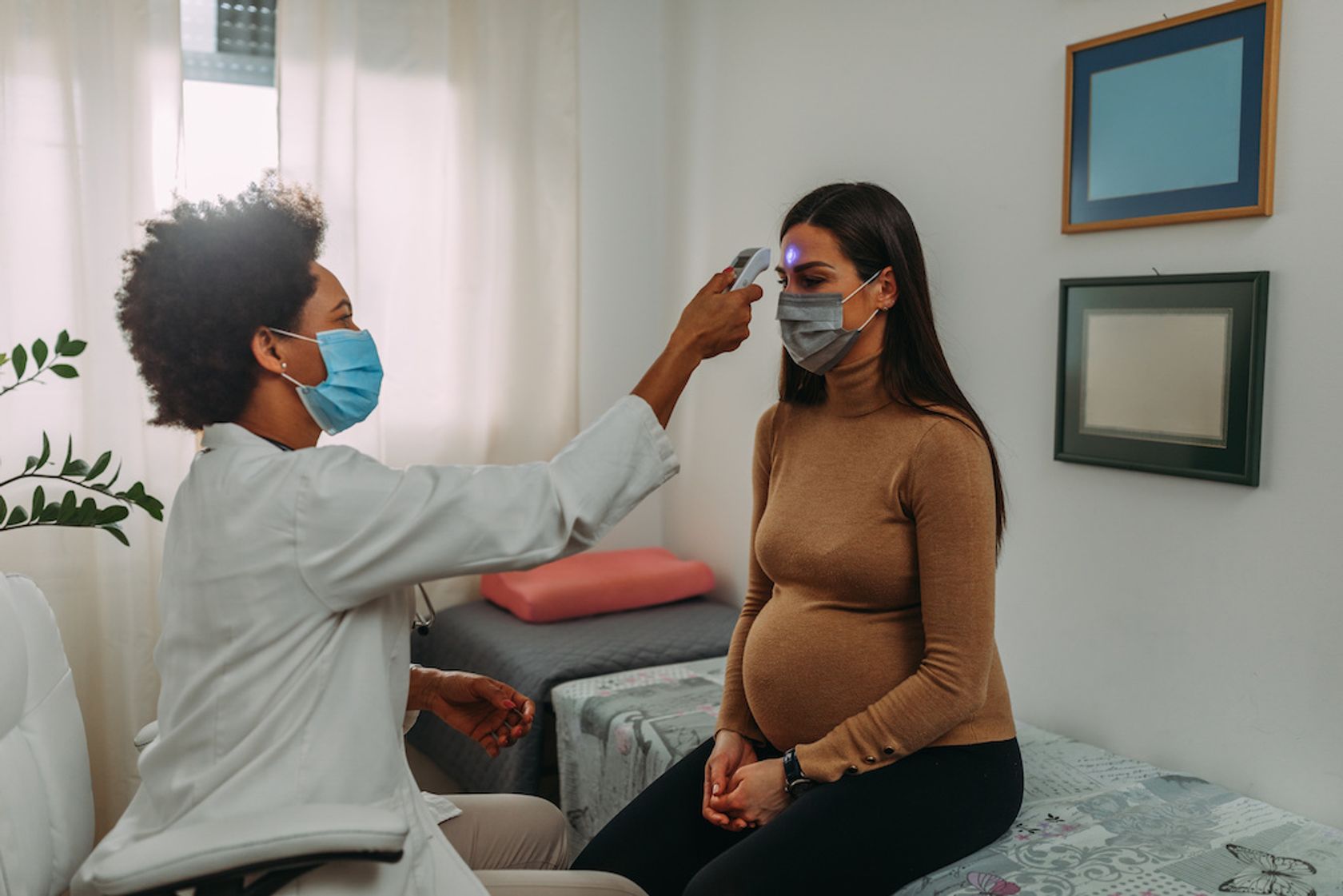 Bei Schwangerer wird in der Arztpraxis mit einem Stirnthermometer geprüft, ob sie Fieber hat.