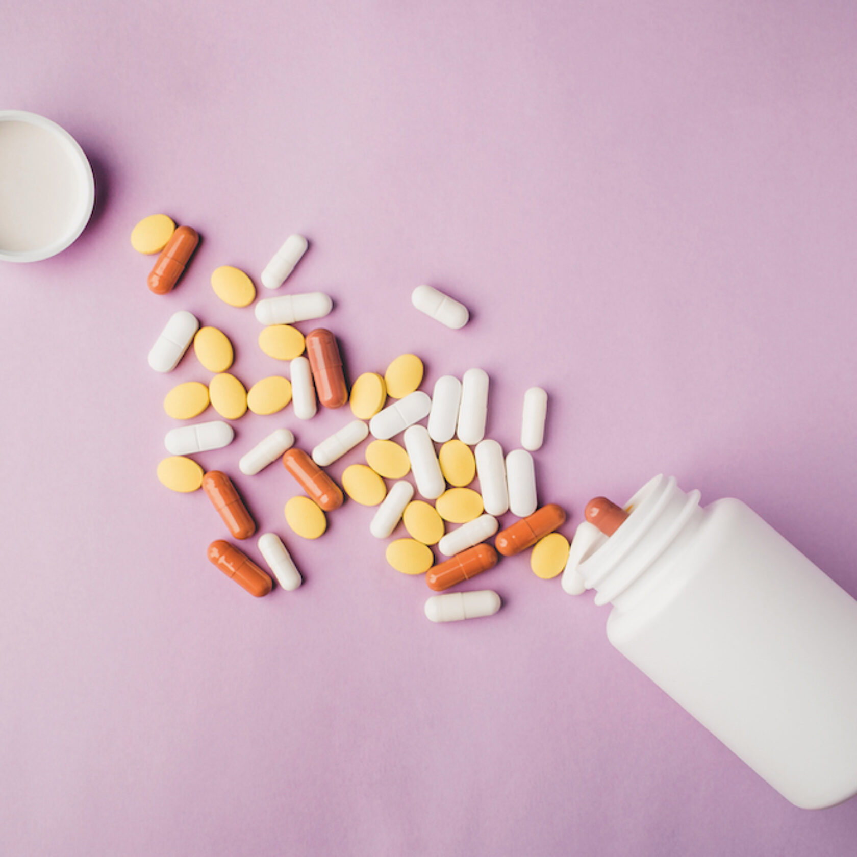 Aus einer Medikamentenflasche sind verschiedenfarbige Tabletten und Kapseln mit verschiedener Form ausgeschüttet