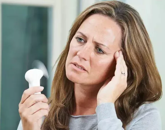 Menopausale Frau mit Ventilator wegen Hitzewallungen
