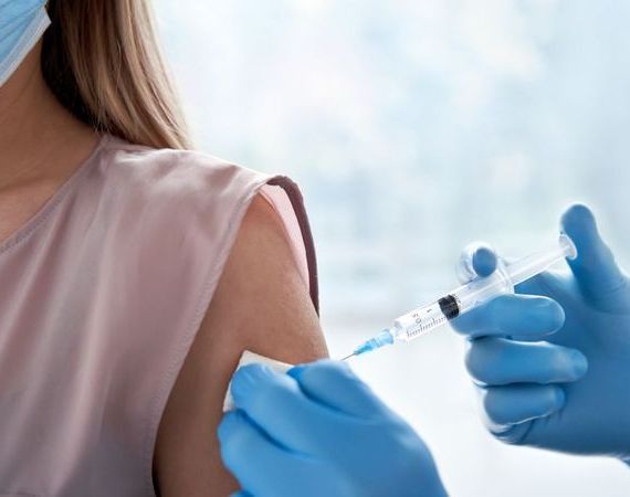Frau erhält eine Impfung in den Oberarm.