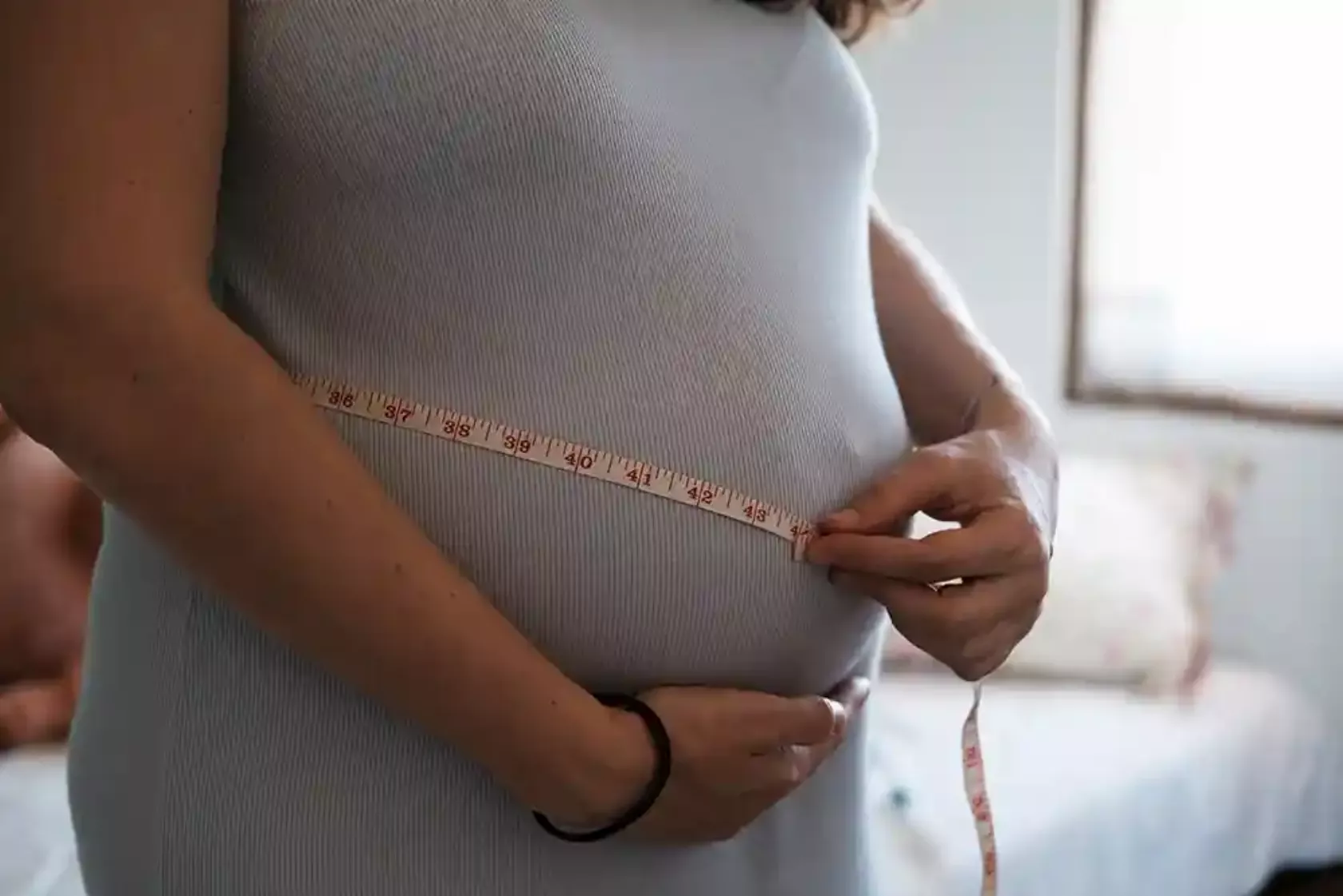 Unkenntliche Schwangere misst ihren Bauchumfang.