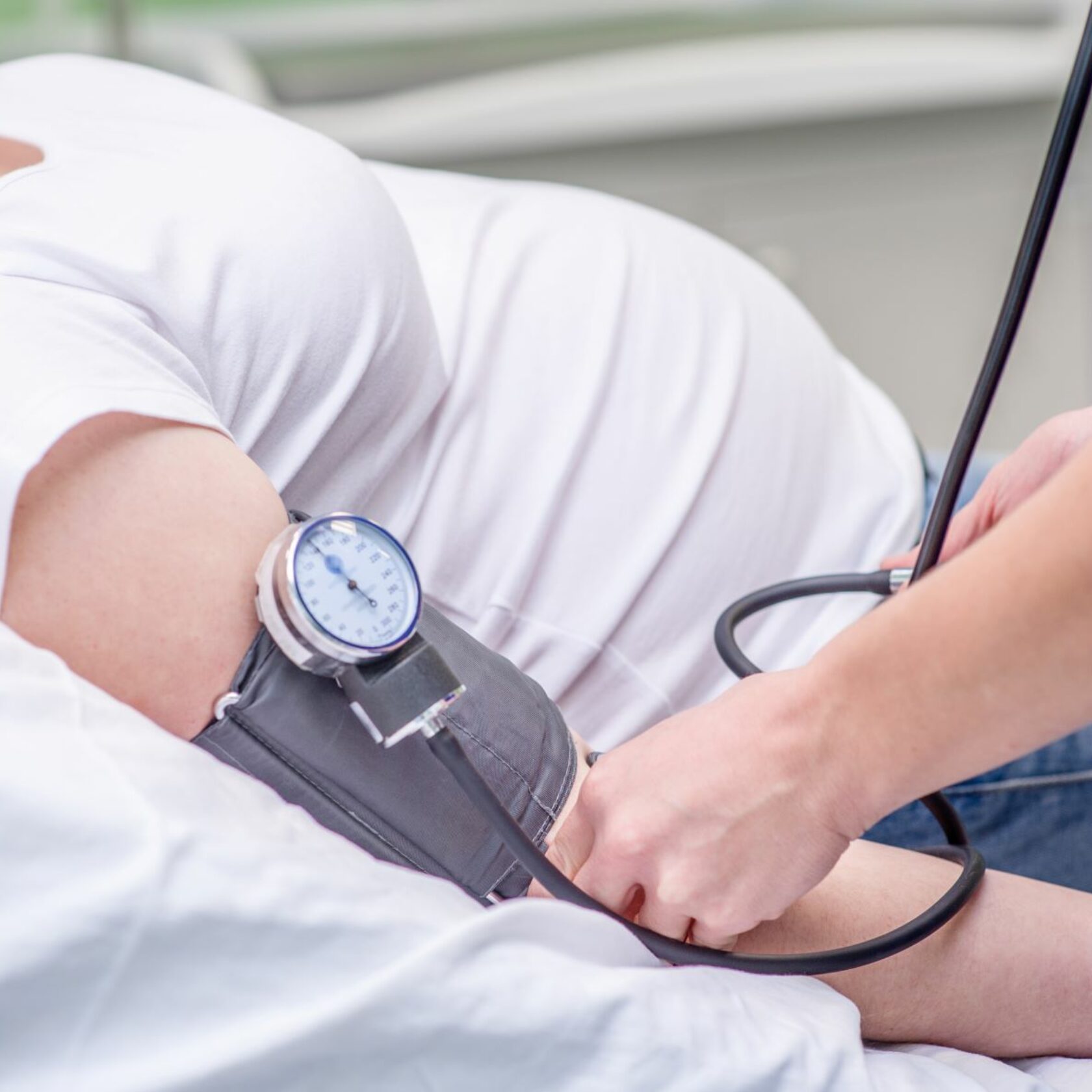 Frau in mittleren Schwangerschaftsmonaten beim Blutdruckmessen in einer Praxis